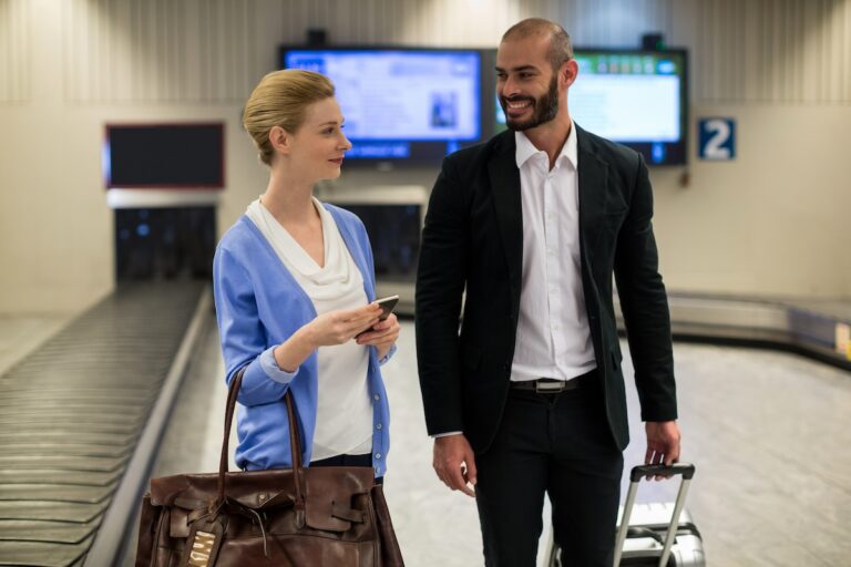 Smiling couple walking with their trolley bags in airport terminal